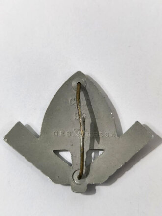 Reichsarbeitsdienst Mützenabzeichen in Leichmetall mit beiden Splinten und Herstellermarkierung. Lackierte Ausführung in sehr gutem Zustand