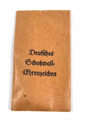 Deutsches Schutzwall  Ehrenzeichen in Verleihungstüte, Band noch im Wickelpapier, Buntmetall, Tüte rückseitig mit Hersteller " E. Ferdinand, Wiedmann, Frankfurt "