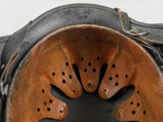 Stahlhelm Modell 1940 der Wehrmacht. Originales Innenfutter, Nieten und Glocke Q66. Neuzeitlich lackiert und mit Emblemen der Polizei versehen, der Kinnriemen ist ebenfalls eine Reproduktion.