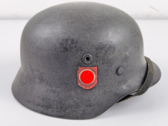 Stahlhelm Modell 1940 der Wehrmacht. Originales Innenfutter, Nieten und Glocke Q66. Neuzeitlich lackiert und mit Emblemen der Polizei versehen, der Kinnriemen ist ebenfalls eine Reproduktion.