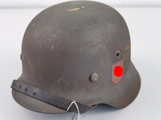 Stahlhelm Modell 1940 der Wehrmacht. Vermutlich in Teilen originales Innenfutter, Nieten und Glocke SE64. Neuzeitlich lackiert und mit Emblemen der Waffen SS versehen, der Kinnriemen ist ebenfalls eine Reproduktion.