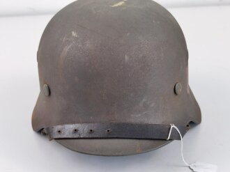 Stahlhelm Modell 1940 der Wehrmacht. Vermutlich in Teilen originales Innenfutter, Nieten und Glocke SE64. Neuzeitlich lackiert und mit Emblemen der Waffen SS versehen, der Kinnriemen ist ebenfalls eine Reproduktion.