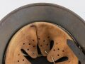 Stahlhelm Modell 1940 der Wehrmacht. Vermutlich in Teilen originales Innenfutter, Nieten und Glocke SE64. Neuzeitlich lackiert und mit Emblemen der Waffen SS versehen, der Kinnriemen ist ebenfalls eine Reproduktion.