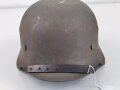 Stahlhelm Modell 1940 der Wehrmacht. Vermutlich in Teilen originales Innenfutter, Nieten und Glocke SE64. Neuzeitlich lackiert und mit Emblemen der Waffen SS versehen, der Kinnriemen ist ebenfalls eine Reproduktion.