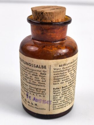 Glasflasche "Hautentgiftungssalbe" datiert 1943. Gesamthöhe 9,5cm.