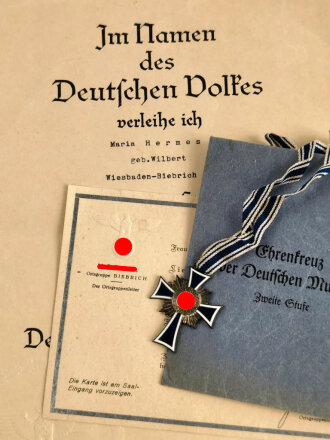 Ehrenkreuz der Deutschen Mutter zweite Stufe, in Tüte von Gottlieb & Wagner Oberstein. Dazu die zugehörige Verleihungsurkunde sowie Einladung zur Feierstunde der NSDAP Ortsgruppe Wiesbaden Biebrich mit eigenhändiger Unterschrift des Ortsgruppenleiter