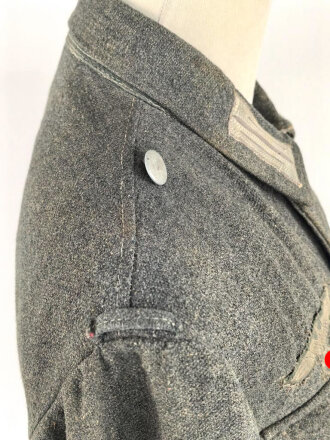 Heer, Feldbluse für Mannschaften Modell 1943. Kammerstück aus italienischem Tuch . Die Kragenspiegel höchstwahrscheinlich original vernäht, der Brustadler ergänzt. Stark getragenes Stück mit diversen älteren Reparaturstellen.
