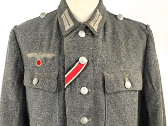 Heer, Feldbluse für Mannschaften Modell 1943. Kammerstück aus italienischem Tuch . Die Kragenspiegel höchstwahrscheinlich original vernäht, der Brustadler ergänzt. Stark getragenes Stück mit diversen älteren Reparaturstellen.