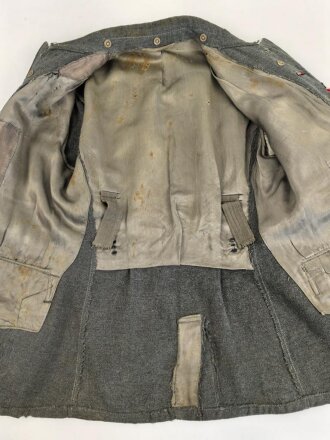 Heer, Feldbluse für Mannschaften Modell 1943. Kammerstück aus italienischem Tuch . Die Kragenspiegel höchstwahrscheinlich original vernäht, der Brustadler ergänzt. Stark getragenes Stück mit diversen älteren Reparaturstellen.