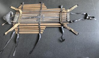 Vorrichtung zum bergen Verwundeter im Gebirge. Die Holzlattung mittig 132cm lang. Sowohl zum hinterherziehen im Schnee als auch zum Abseilen gedacht. Ungereinigtes Stück