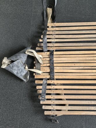 Vorrichtung zum bergen Verwundeter im Gebirge. Die Holzlattung mittig 132cm lang. Sowohl zum hinterherziehen im Schnee als auch zum Abseilen gedacht. Ungereinigtes Stück