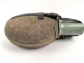Feldflasche Wehrmacht, Hersteller WAL, belederung unten defekt, sonst sehr guter Zustand, mit zugehöriger Aufschiebeschlaufe. Variante mit grünmeliertem Preßmasse Trinkbecher