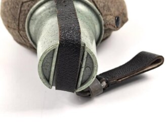 Feldflasche Wehrmacht, Hersteller WAL, belederung unten defekt, sonst sehr guter Zustand, mit zugehöriger Aufschiebeschlaufe. Variante mit grünmeliertem Preßmasse Trinkbecher