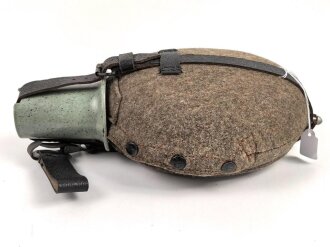 Feldflasche Wehrmacht, Hersteller WAL, belederung unten defekt, sonst sehr guter Zustand, mit zugehöriger Aufschiebeschlaufe. Variante mit grünmeliertem Preßmasse Trinkbecher