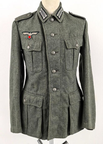 Heer, Feldbluse Modell 1940 für einen Obergefreiten der Kraftfahrtruppe. Leicht getragenes Kammerstück von 1941 . Die Kragenspiegel maschinenvernäht, der Brustadler von Hand. Im Rückenbereich diverse kleinere Schäden, sonst gut