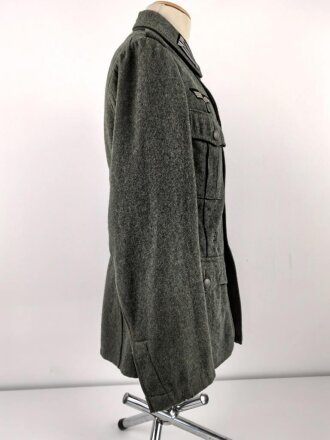 Heer, Feldbluse Modell 1940 für einen Obergefreiten der Kraftfahrtruppe. Leicht getragenes Kammerstück von 1941 . Die Kragenspiegel maschinenvernäht, der Brustadler von Hand. Im Rückenbereich diverse kleinere Schäden, sonst gut