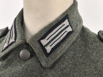 Heer, Feldbluse Modell 1940 für einen Obergefreiten der Kraftfahrtruppe. Leicht getragenes Kammerstück von 1941 . Die Kragenspiegel maschinenvernäht, der Brustadler von Hand. Im Rückenbereich diverse kleinere Schäden, sonst gut