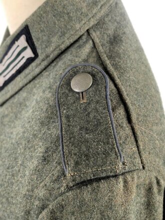 Heer, Feldbluse Modell 1940 für einen Obergefreiten der Kraftfahrtruppe. Leicht getragenes Kammerstück von 1941 . Die Kragenspiegel maschinenvernäht, der Brustadler von Hand. Im Rückenbereich diverse kleinere Schäden, sonst gut