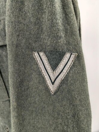 Heer, Feldbluse Modell 1940 für einen Obergefreiten der Kraftfahrtruppe. Leicht getragenes Kammerstück von 1941 . Die Kragenspiegel maschinenvernäht, der Brustadler von Hand. Im Rückenbereich diverse kleinere Schäden, sonst gut