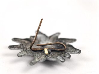 Traditionsedelweiss für die Schirmmütze von Angehörigen der Gebirgstruppe der Wehrmacht. Wird zwischen Eichenlaub und Adler getragen. Fertigung aus Zink, versilbert