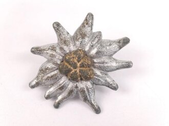 Traditionsedelweiss für die Schirmmütze von Angehörigen der Gebirgstruppe der Wehrmacht. Wird zwischen Eichenlaub und Adler getragen. Fertigung aus Zink, versilbert