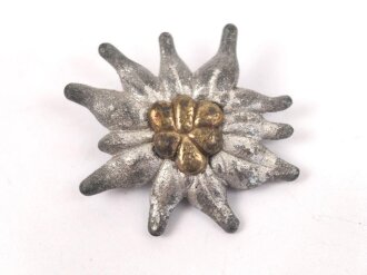 Traditionsedelweiss für die Schirmmütze von Angehörigen der Gebirgstruppe der Wehrmacht. Wird zwischen Eichenlaub und Adler getragen. Fertigung aus Zink, versilbert