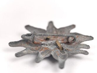 Traditionsedelweiss für die Schirmmütze von Angehörigen der Gebirgstruppe der Wehrmacht. Wird zwischen Eichenlaub und Adler getragen. Fertigung aus Zink, versilbert