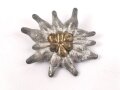 Traditionsedelweiss für die Schirmmütze von Angehörigen der Gebirgstruppe der Wehrmacht. Wird zwischen Eichenlaub und Adler getragen. Fertigung aus Zink, versilbert