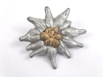Traditionsedelweiss für die Schirmmütze von Angehörigen der Gebirgstruppe der Wehrmacht. Wird zwischen Eichenlaub und Adler getragen. Fertigung aus Zink, versilbert