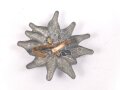 Traditionsedelweiss für die Schirmmütze von Angehörigen der Gebirgstruppe der Wehrmacht. Wird zwischen Eichenlaub und Adler getragen. Fertigung aus Zink, versilbert