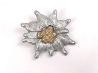 Traditionsedelweiss für die Schirmmütze von Angehörigen der Gebirgstruppe der Wehrmacht. Wird zwischen Eichenlaub und Adler getragen. Fertigung aus Zink, versilbert, ein Splint fehlt