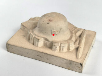 Erinnerungsgegenstand aus Giesmasse, Darstellend einen Stahlhelm des Heeres samt Ausrüstung für einen Infanteristen. Maße 8,5 x 12cm. Ungereinigtes Stück