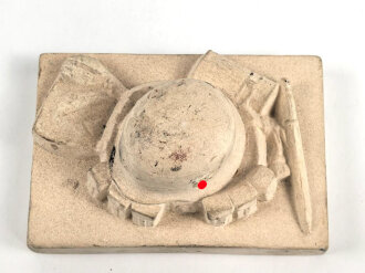 Erinnerungsgegenstand aus Giesmasse, Darstellend einen Stahlhelm des Heeres samt Ausrüstung für einen Infanteristen. Maße 8,5 x 12cm. Ungereinigtes Stück