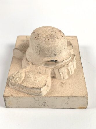 Erinnerungsgegenstand aus Giesmasse, Darstellend einen Stahlhelm des Heeres samt Ausrüstung für einen Infanteristen. Maße 8,5 x 12cm. Ungereinigtes Stück