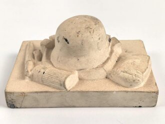 Erinnerungsgegenstand aus Giesmasse, Darstellend einen Stahlhelm des Heeres samt Ausrüstung für einen Infanteristen. Maße 8,5 x 12cm. Ungereinigtes Stück