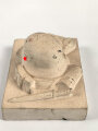 Erinnerungsgegenstand aus Giesmasse, Darstellend einen Stahlhelm des Heeres samt Ausrüstung für einen Infanteristen. Maße 8,5 x 12cm. Ungereinigtes Stück