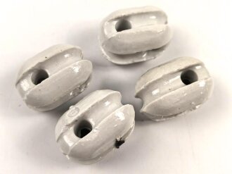 Vier Isolatoren aus weissem Porzellan.