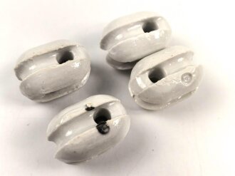 Vier Isolatoren aus weissem Porzellan.
