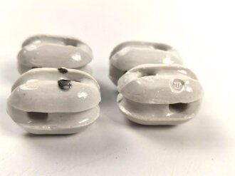 Vier Isolatoren aus weissem Porzellan.