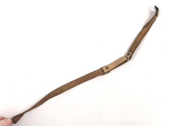 Kinnriemen für einen Tropenhelm der Wehrmacht. An der Befestigung ausgerissen, Gesamtlänge wie fotografiert 45cm. Ungereinigt, leicht angetrocknet