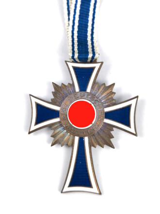 Ehrenkreuz der Deutschen Mutter in bronze, an langem Band. Nicht verausgabtes Stück, aus altem Bestand eines höchstwahrscheinlich Österreichischen Herstellers.