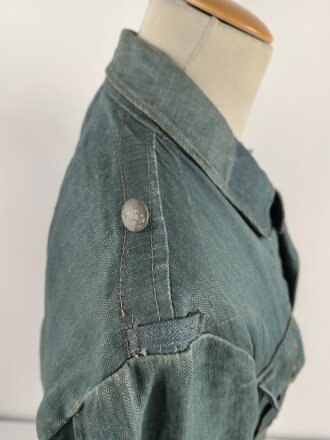 Feldbluse in Drillichmaterial. Heeresschnitt, aber eher Polizeigrünes Material. Weder Brust- noch Ärmeladlerabdruck, dafür deutliche , relativ große Kragenspiegelabdrücke. Getragenes Kammerstück