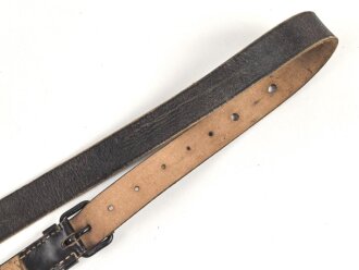 Lederriemen geschwärzt, lackierte Eisenschliesse, eiserne Karabinerhaken, Breite knapp 3cm, Länge etwa 125cm, Alter und Herkunft unbekannt