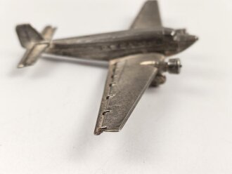 Kleines Metallflugzeug, wohl eine Junkers Ju52 darstellend. Flügelspannweite 14,5cm, die Propeller fehlen.
