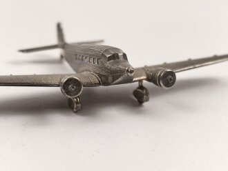 Kleines Metallflugzeug, wohl eine Junkers Ju52 darstellend. Flügelspannweite 14,5cm, die Propeller fehlen.