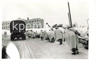 Angehörige des Heeres in Wintertarnbekleidung beim ziehen von Schlitten, rückseitig beschriftet "Smolensk", Maße 9 x 14 cm