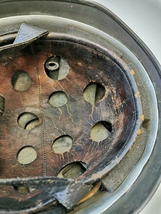 Luftwaffe, Stahlhelm für Angehörige der Fallschirmtruppen Modell 1938.  Spätes Stück mit originaler Tarnlackierung. Innenfutter zum Teil oberflächlich rissig aber weich. Zusammengehöriger, getragener Helm.